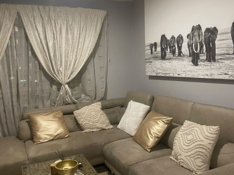 A cozy living room area featuring neutral wall tones and recessed ceiling lighting, providing a comfortable and inviting space for relaxation.