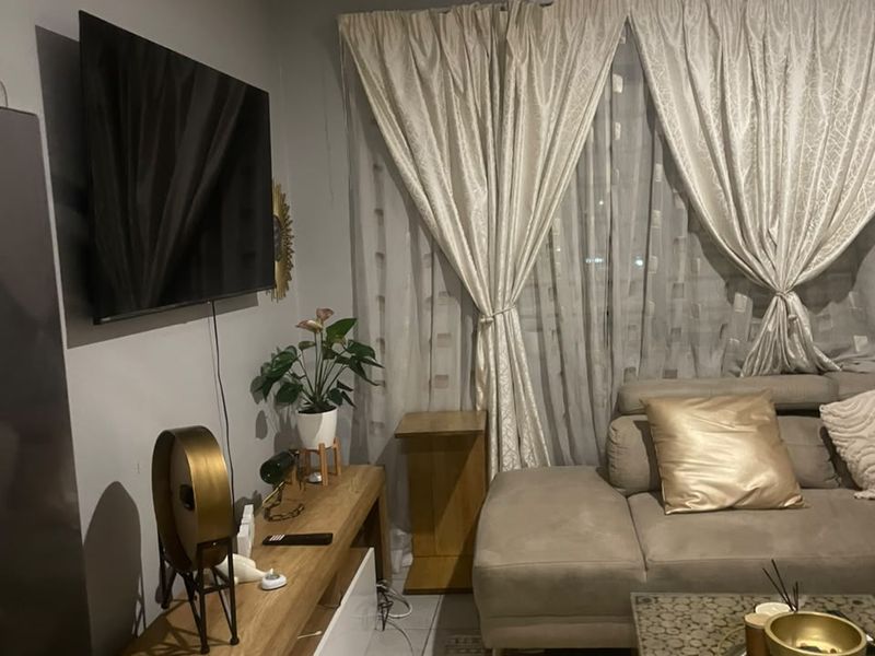 A cozy living room area featuring tiled flooring and a wall-mounted television setup, providing a functional space for relaxation.