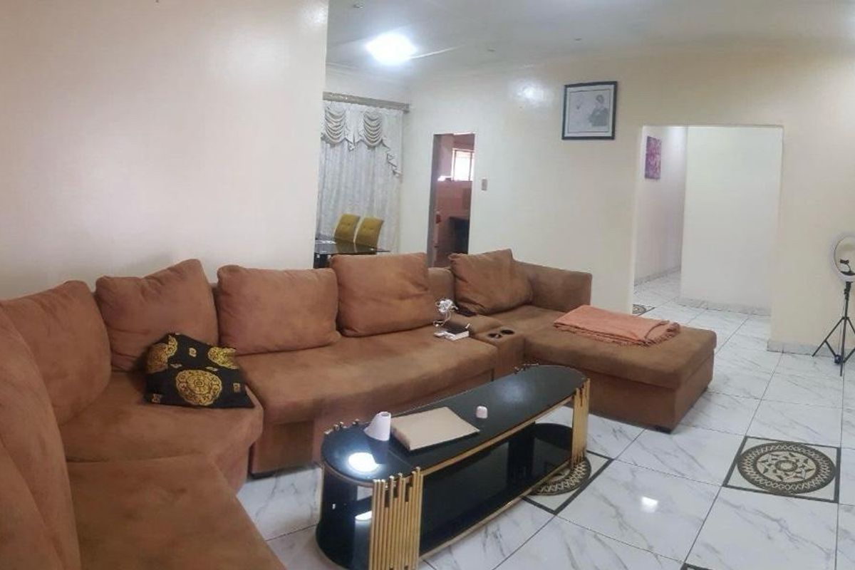 A spacious living room featuring polished tiled flooring, recessed ceiling lighting, and built-in wall shelving, offering a neutral base for interior design.