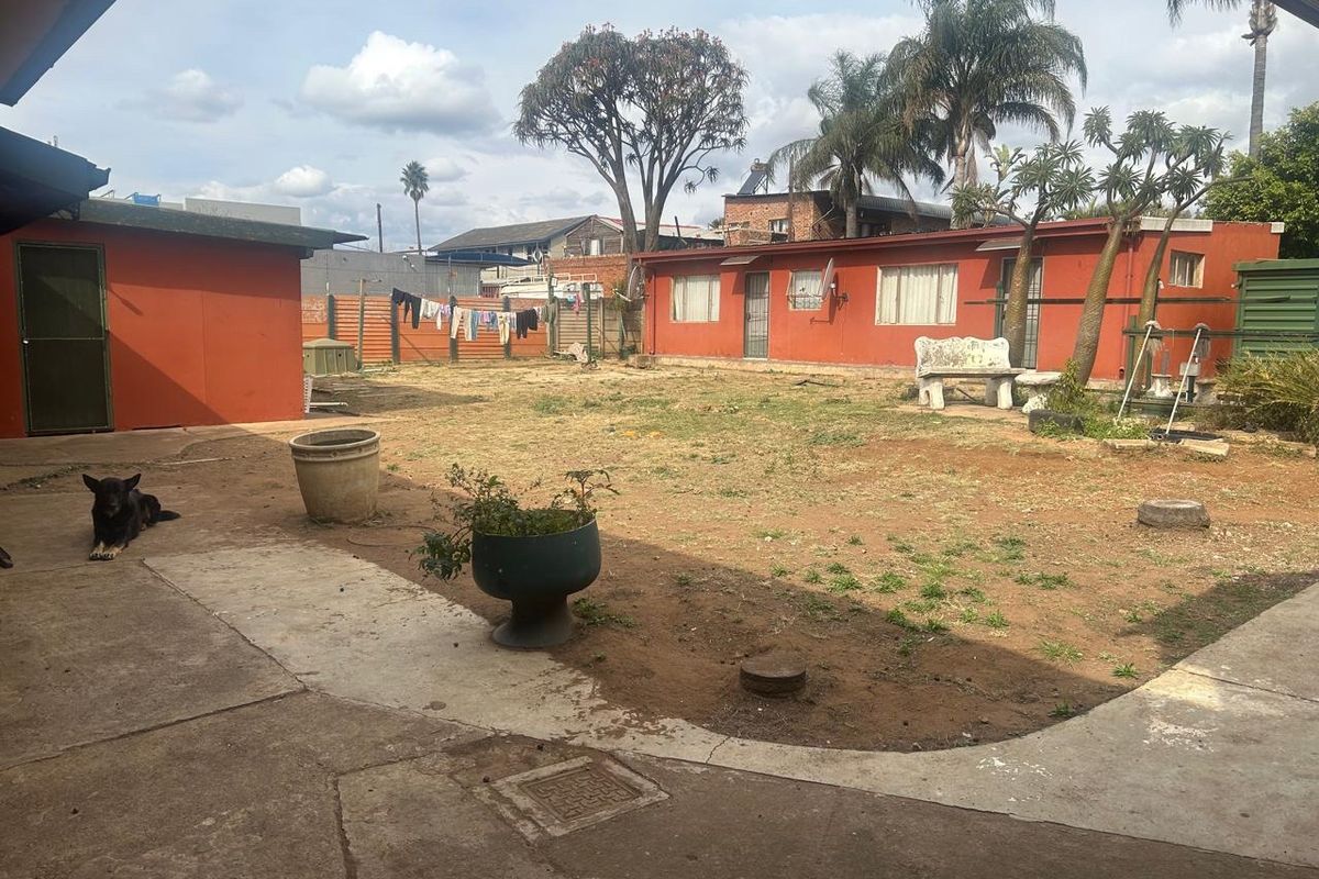 Spacious rear yard featuring a concrete patio area and perimeter fencing, offering potential for landscaping and outdoor improvement.