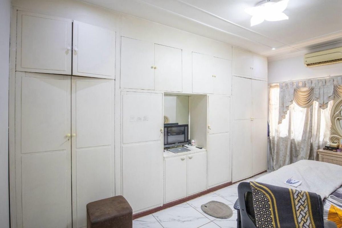 Bedroom featuring extensive floor-to-ceiling built-in cupboards, tiled flooring, and a wall-mounted air conditioning unit.