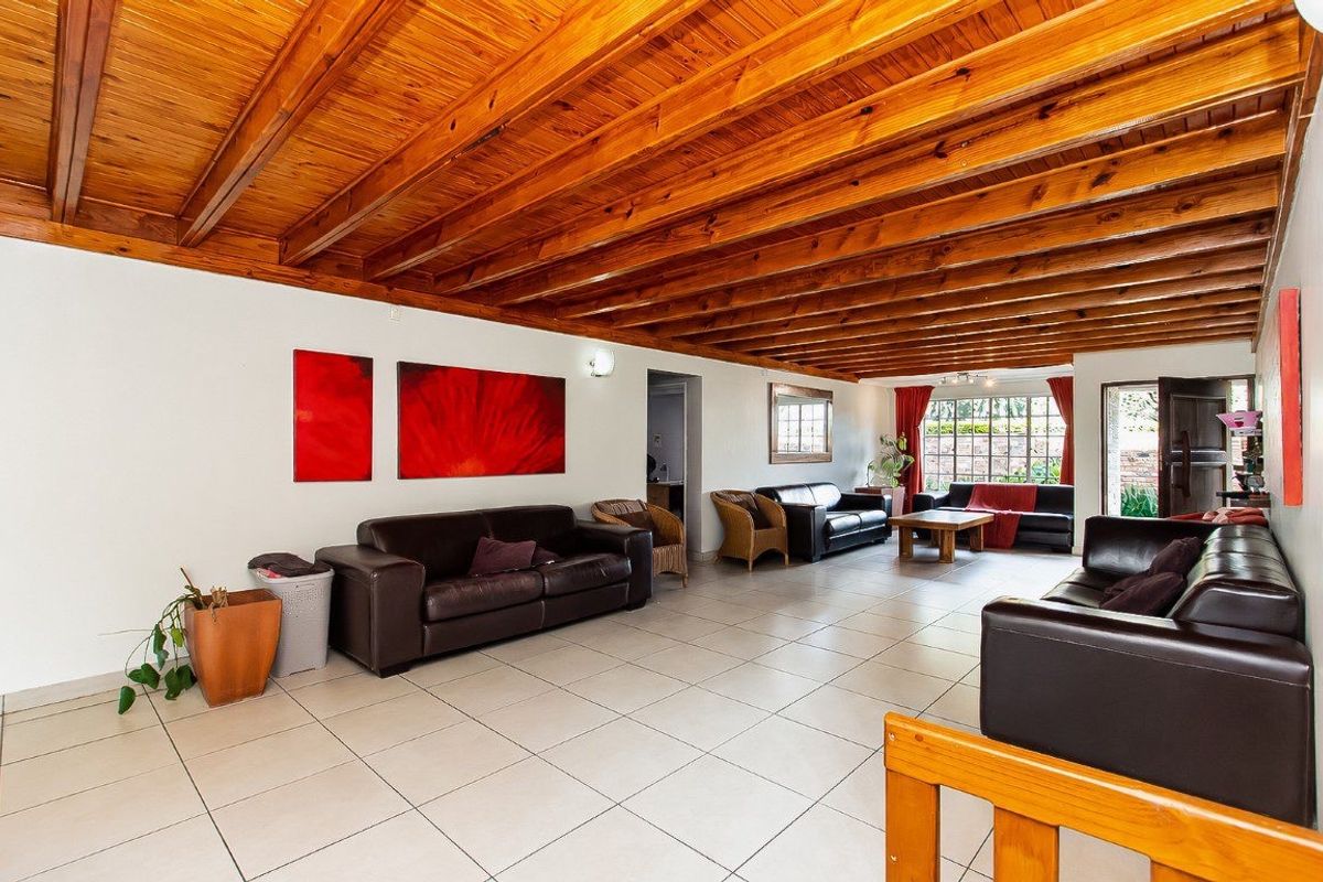 Spacious living area featuring a distinctive exposed timber beam ceiling and neutral ceramic floor tiles, offering a bright and open layout.