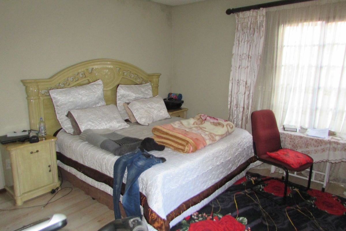 A bedroom featuring laminate flooring and curtain rails, showing visible signs of ceiling water damage.