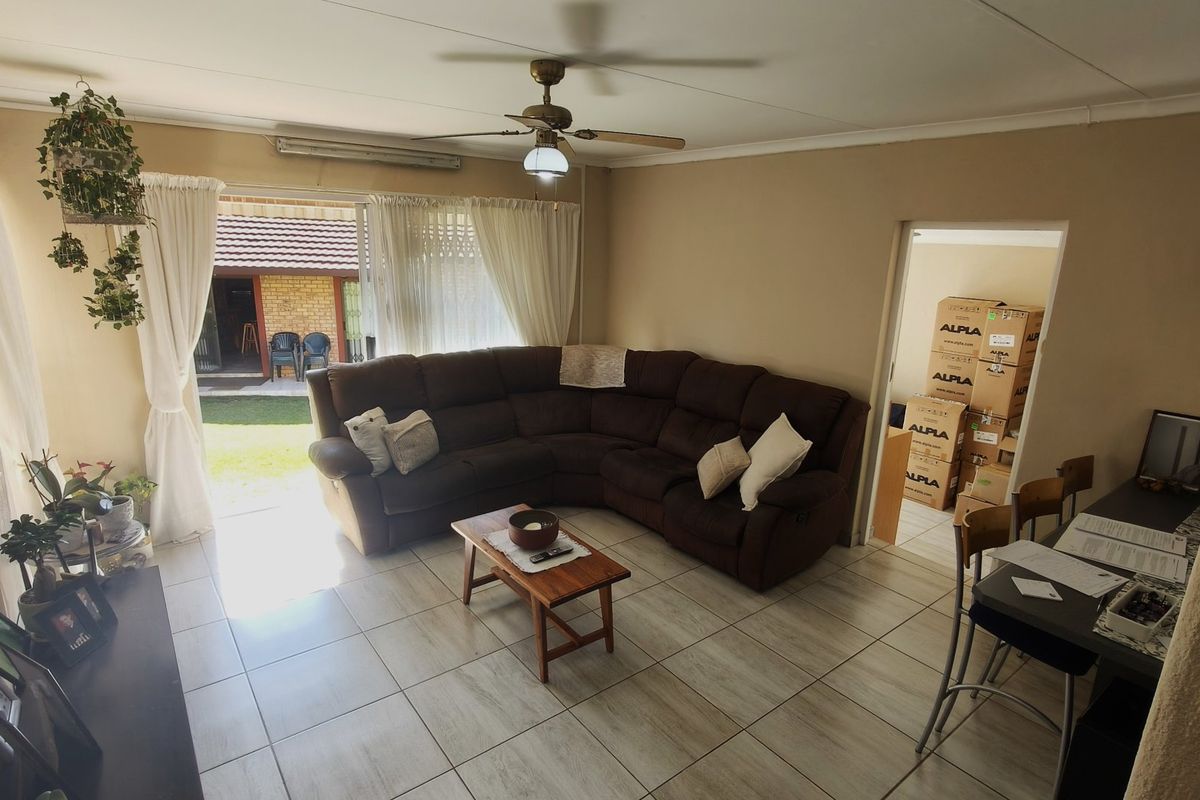 A living room featuring tiled flooring, a ceiling fan, and a sliding glass door providing access to the outdoor area.