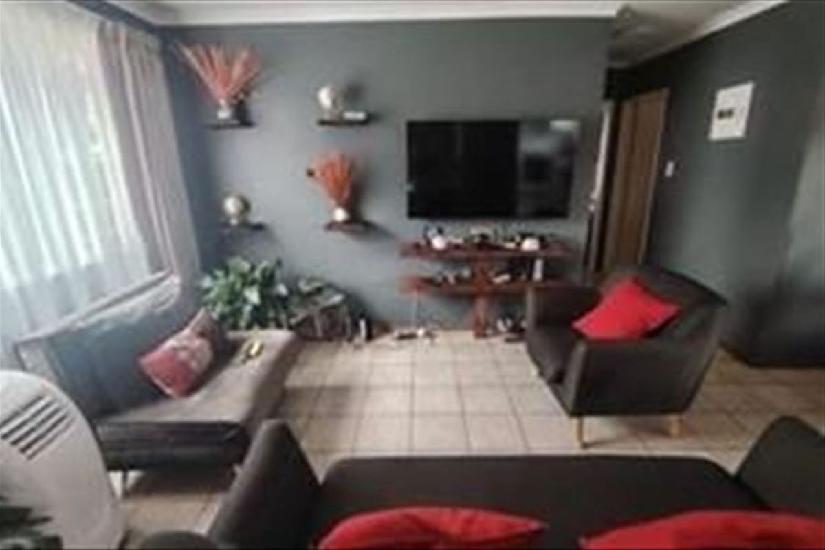 A living room featuring tiled flooring and dark-toned walls, providing a functional space for relaxation and entertainment.