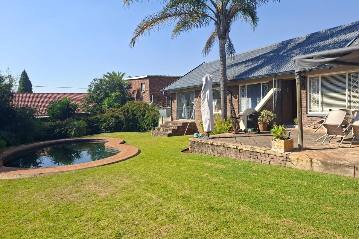 Rear garden featuring a swimming pool, paved patio area, and established landscaping, providing a functional outdoor space for relaxation and entertainment.