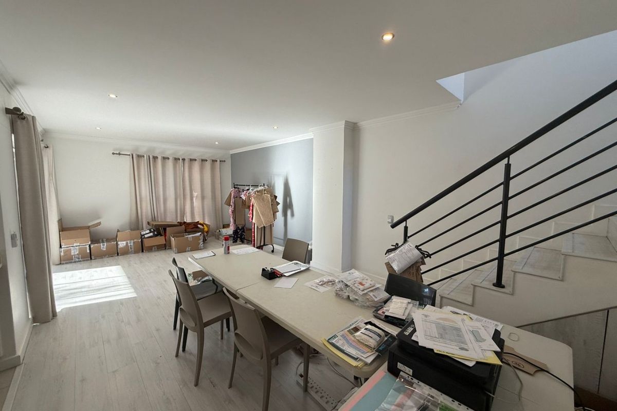 Open-plan living area featuring light laminate flooring, recessed downlighting, and a staircase with a modern metal balustrade.