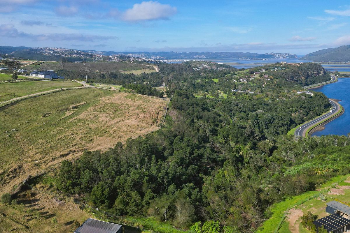 An aerial view of the vacant residential land, showcasing the surrounding landscape, natural vegetation, and proximity to the nearby estuary and road infrastructure.
