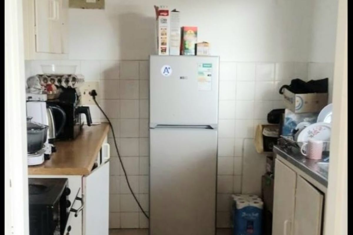 A compact, functional kitchen featuring tiled flooring, a tiled splashback, laminate countertops, and built-in cabinetry with a stainless steel sink.