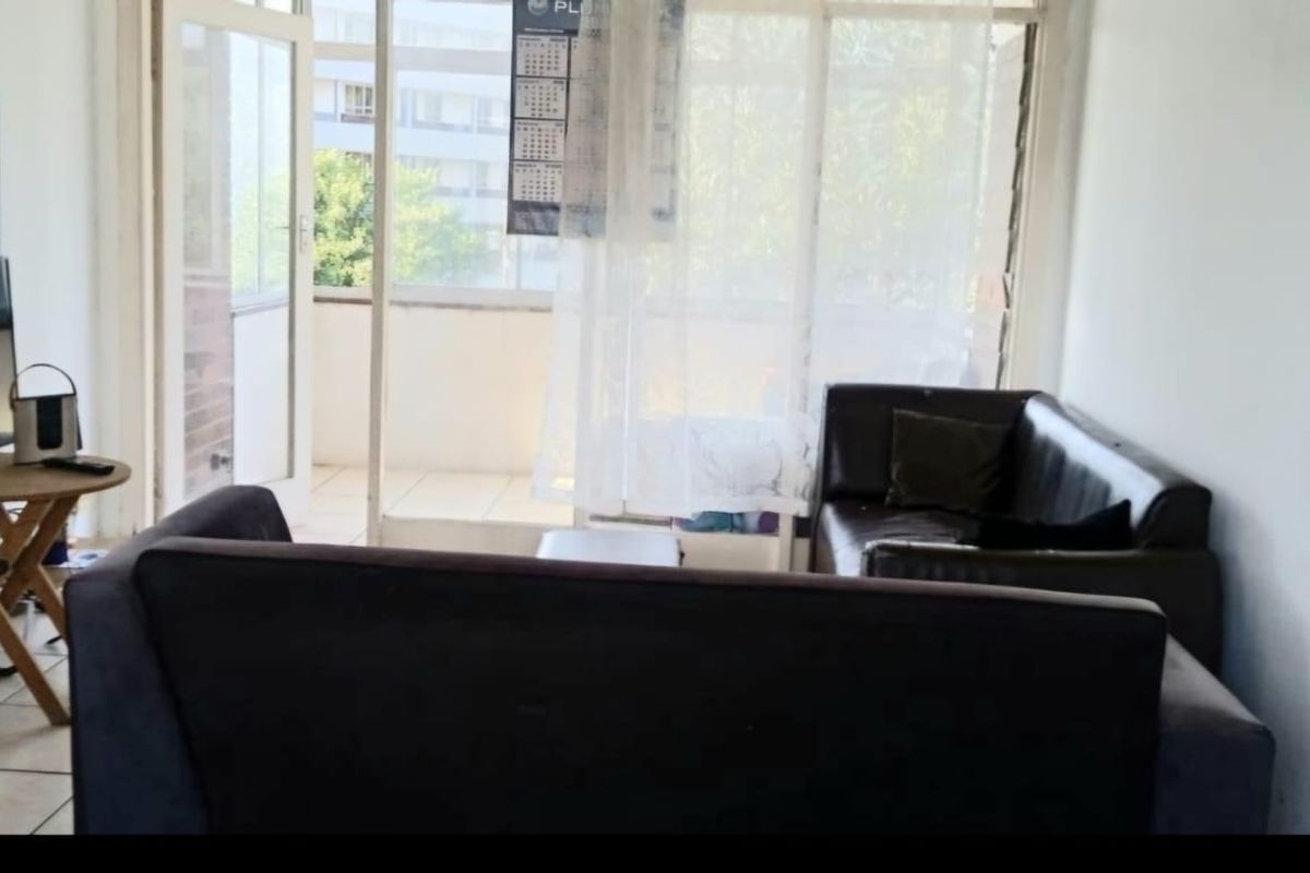 A living room area featuring tiled flooring and direct access to an outdoor balcony through a sliding glass door.