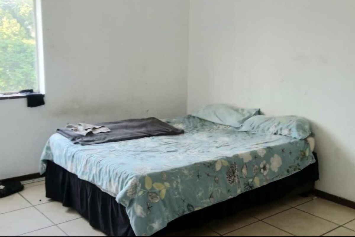 A bedroom featuring tiled flooring and a window, currently requiring wall maintenance and cosmetic updates to improve its overall condition.