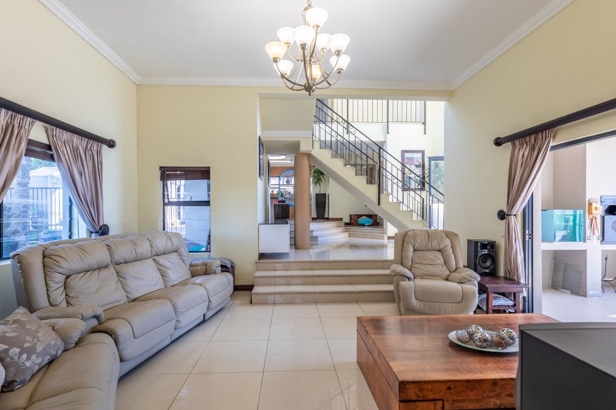 Spacious living room featuring tiled floors, a central staircase with metal railings, and direct access to an outdoor patio area.