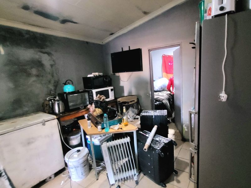 A kitchen area showing significant signs of wear, including wall staining and ceiling damage, requiring substantial renovation and repair to restore functionality.