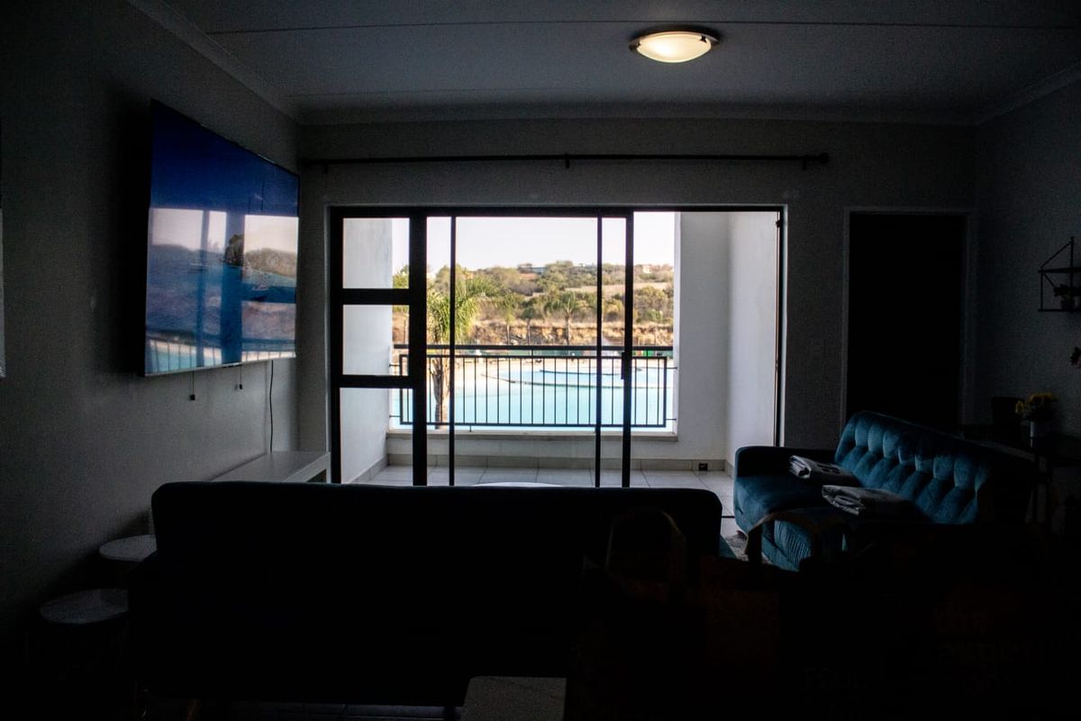 Living room featuring a sliding glass door that opens onto a balcony with views of the pool area.
