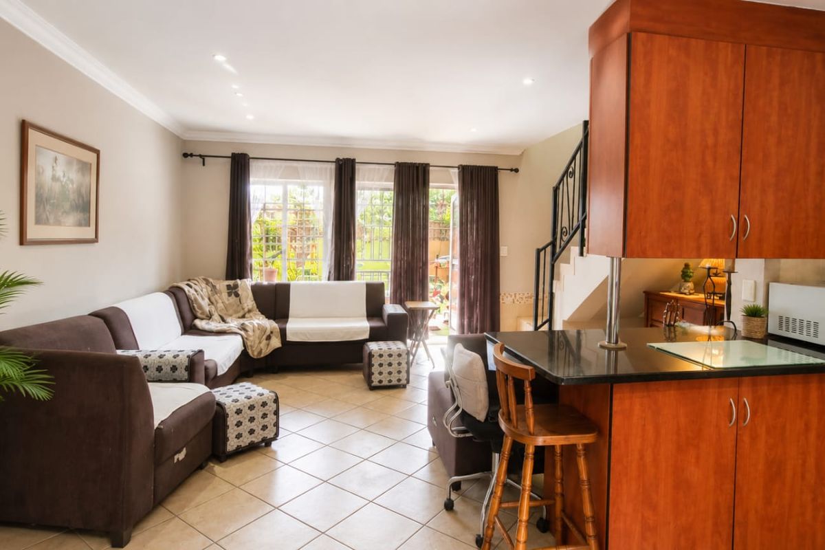 Open plan living area featuring a kitchen with granite countertops and wooden cabinetry, flowing into a lounge space with direct access to the patio.