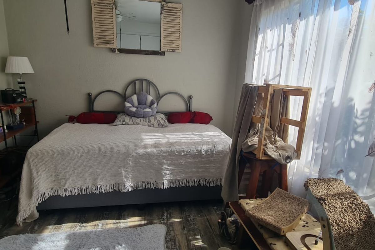 A bedroom featuring laminate flooring and a large sliding glass door that provides natural light.