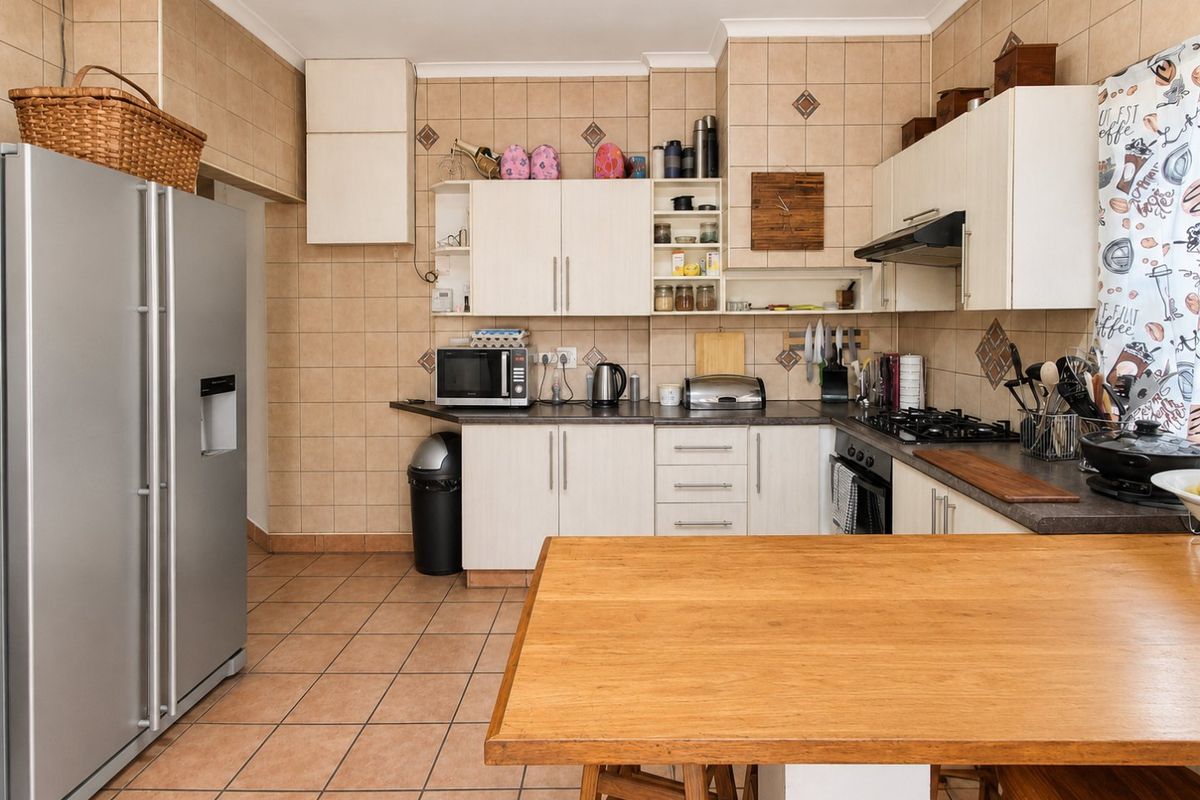 A functional kitchen featuring built-in cabinetry, tiled splashbacks, gas hob, and oven, offering a practical layout with ample storage and workspace.