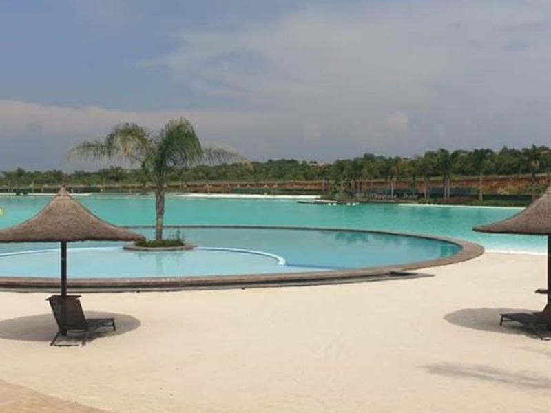 A large, well-maintained swimming pool area featuring a sandy beach entry and landscaped surroundings, providing a resort-style outdoor living experience.