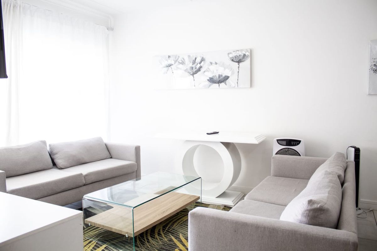 A bright and neutral living room featuring clean white walls and ample natural light, providing a versatile space for relaxation.