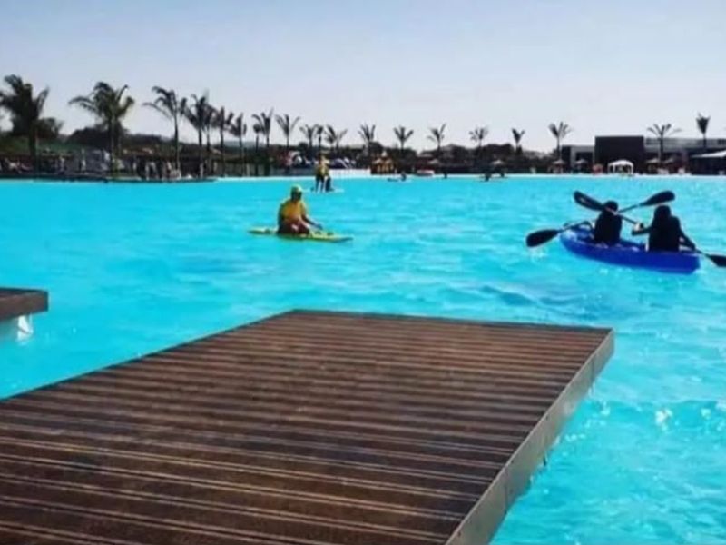 A large recreational swimming lagoon featuring floating docks and clear blue water, set within a landscaped estate environment.