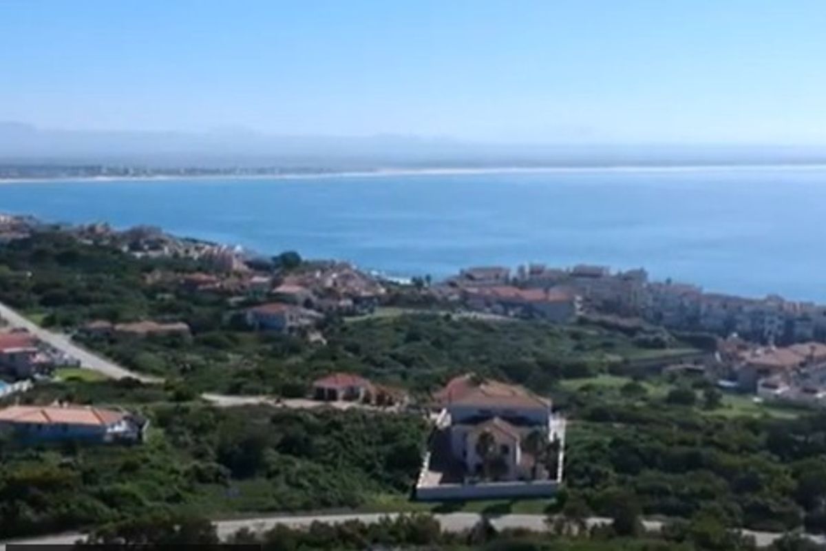 An elevated aerial view showcasing the coastal landscape, surrounding residential properties, and the nearby ocean.