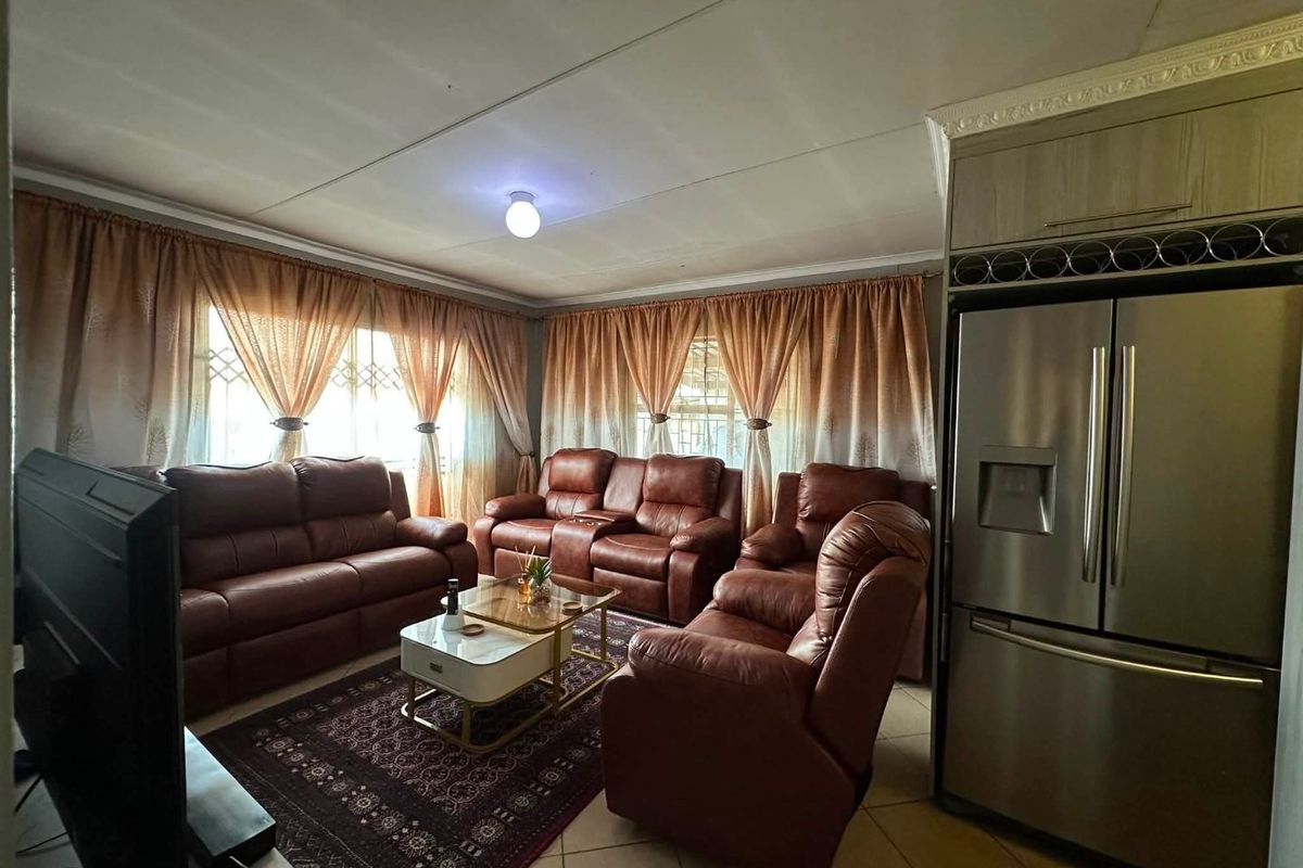 A comfortable living room featuring tiled flooring, decorative ceiling cornices, and security gates on the windows, providing a functional and secure living space.