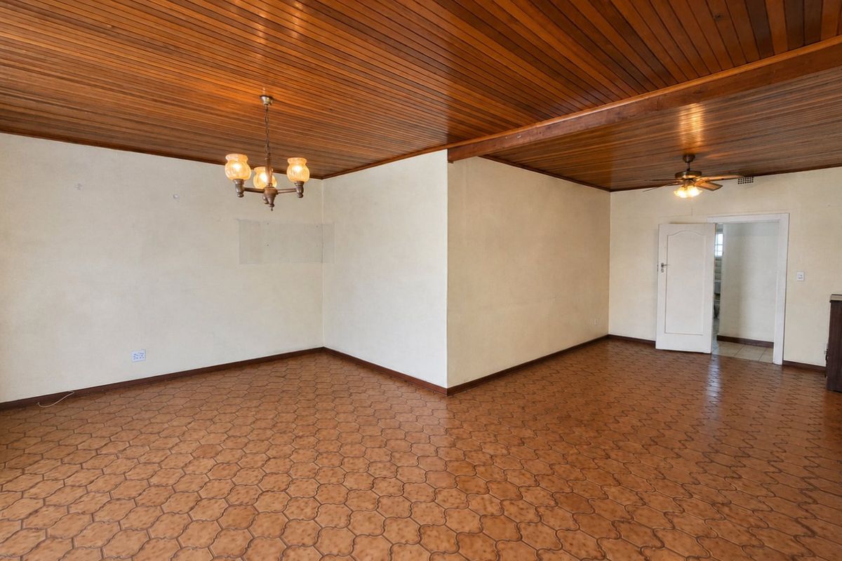 Spacious living area featuring a distinctive timber-clad ceiling, ceramic tile flooring, and a ceiling fan, offering a blank canvas for interior design.
