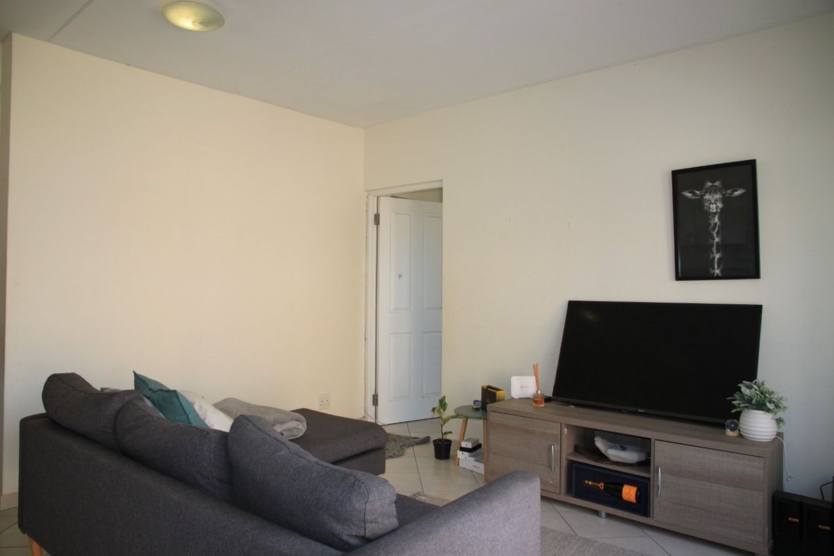 A living room area featuring neutral wall finishes and tiled flooring, providing a functional space for relaxation.