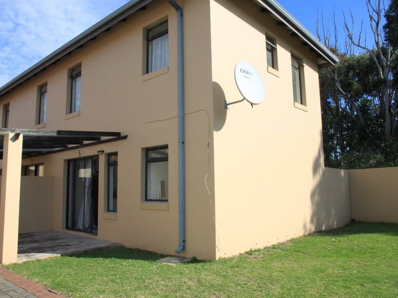 Rear view of the apartment featuring a paved patio area, pergola, and a private garden space with a boundary wall.