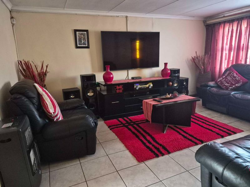 A living room featuring tiled flooring and wall-mounted television setup with visible electrical conduit.