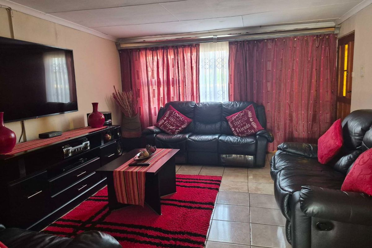 A comfortable living room featuring tiled flooring and large window treatments, providing a functional space for relaxation and entertainment.