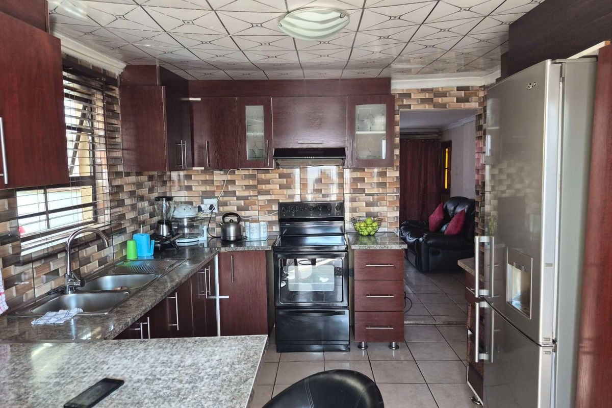 A functional kitchen featuring dark wood cabinetry, granite countertops, a built-in oven with extractor fan, and a tiled backsplash.
