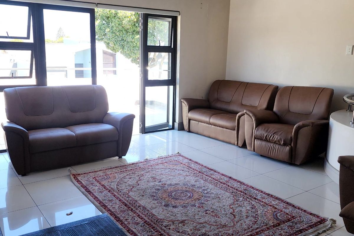 A bright living room featuring large sliding glass doors, polished tiled flooring, and a built-in fireplace, offering a clean and functional living space.