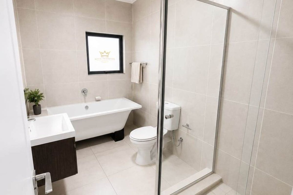 Modern bathroom featuring a freestanding bathtub, separate glass-enclosed shower, wall-mounted vanity, and neutral floor-to-ceiling tiling.