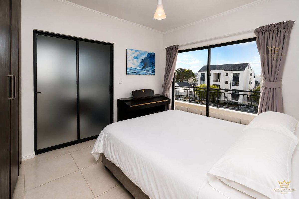 A bright bedroom featuring tiled flooring, a built-in wardrobe with frosted glass doors, and a sliding door providing access to a private balcony.