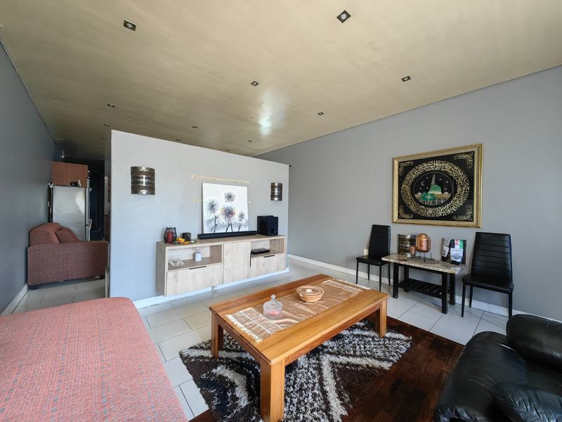 Spacious living area featuring a mix of tiled and parquet flooring, recessed lighting, and a central partition wall with built-in cabinetry.