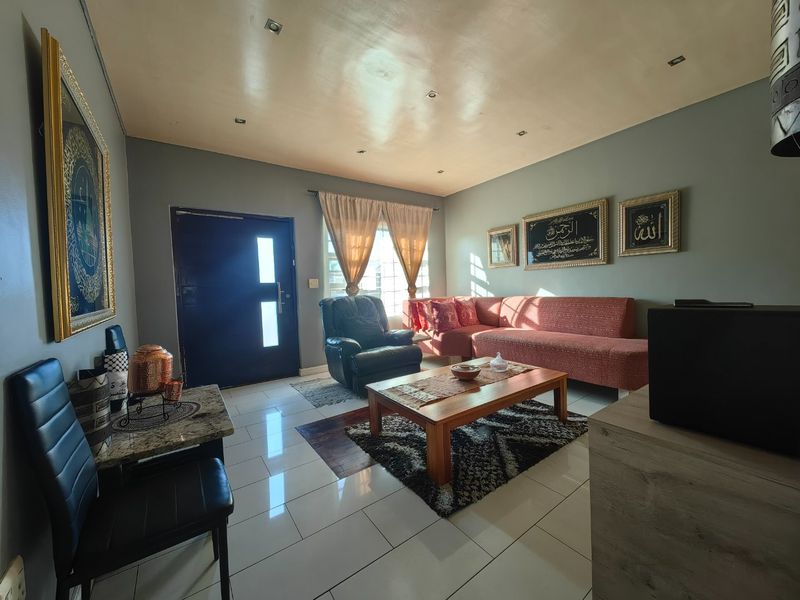 A well-maintained living room featuring tiled flooring, recessed ceiling lighting, and a solid entrance door, creating a comfortable and functional living space.