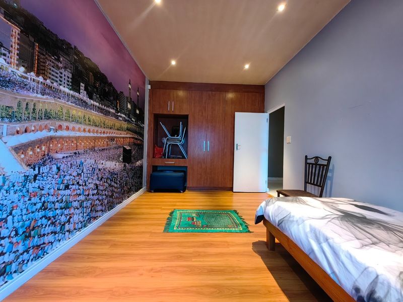 A bedroom featuring laminate flooring, recessed downlighting, and extensive built-in wooden cabinetry for storage.