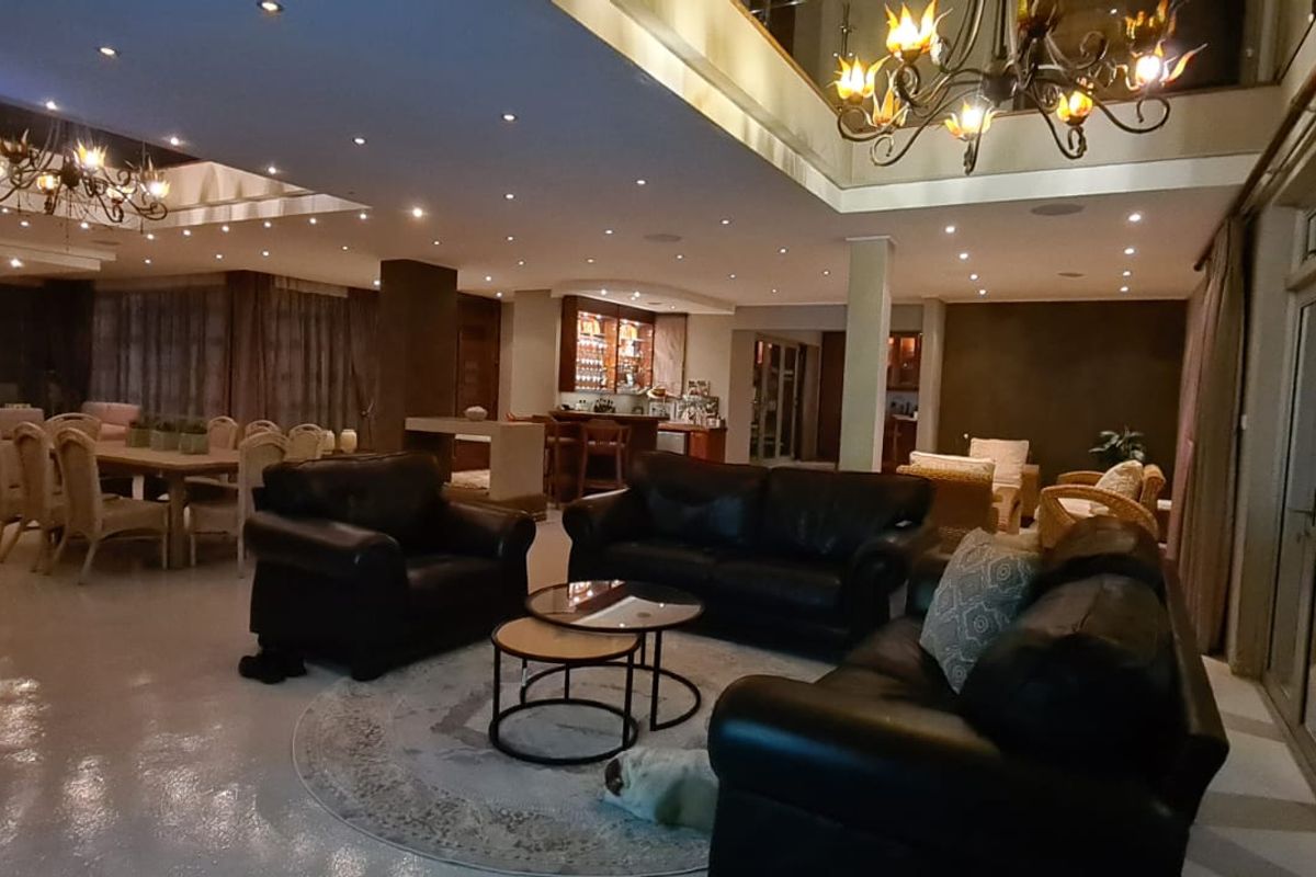 Spacious open-plan living and dining area featuring a built-in bar, double volume ceilings, and large sliding glass doors leading to the exterior.