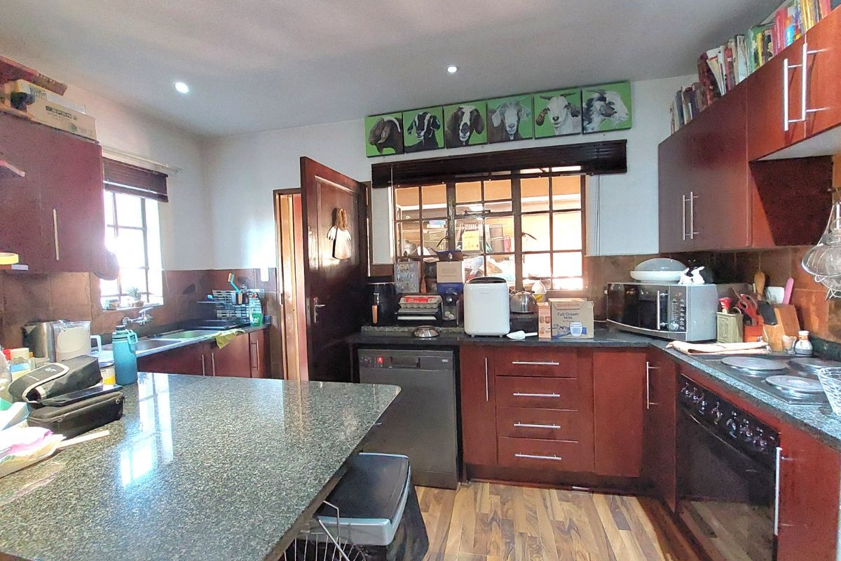 A functional kitchen featuring dark wood cabinetry, granite countertops, a built-in oven, and a breakfast island, offering ample workspace and storage.