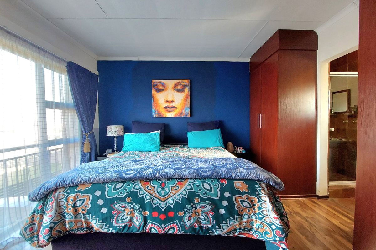 A bedroom featuring laminate flooring, a built-in wardrobe, and direct access to a balcony through a sliding door.