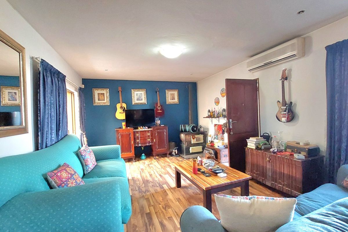 A living room featuring wood-look flooring, a wood-burning stove, and a wall-mounted split-system air conditioner.
