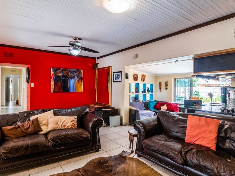 Spacious open-plan living area featuring tiled floors, a ceiling fan, and a breakfast bar connecting to an adjacent lounge space.