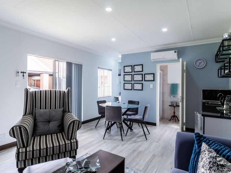 An open-plan living and kitchenette area featuring modern tiled flooring, recessed lighting, a split-system air conditioner, and direct access to an outdoor space.