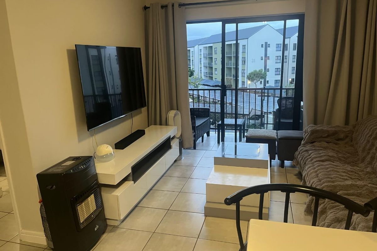 A living room featuring tiled flooring and a large sliding glass door providing access to an outdoor balcony area.
