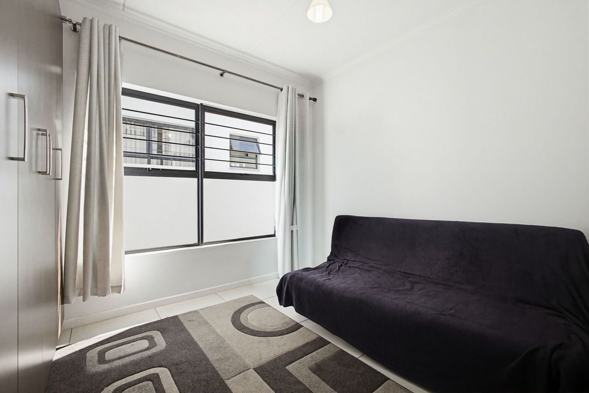 A bedroom featuring tiled flooring, a built-in wardrobe, and a window fitted with security bars.