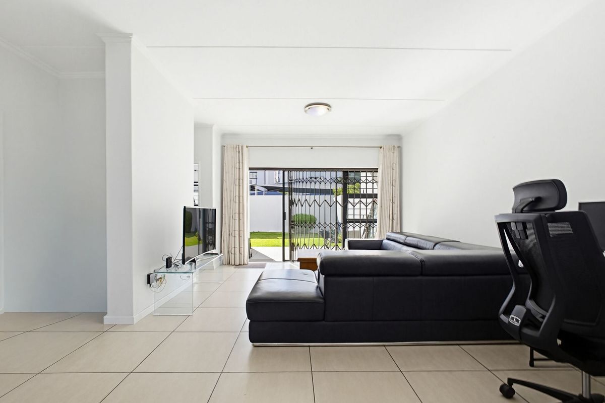 Bright living room featuring neutral tiled flooring and a sliding glass door providing direct access to the rear garden area.