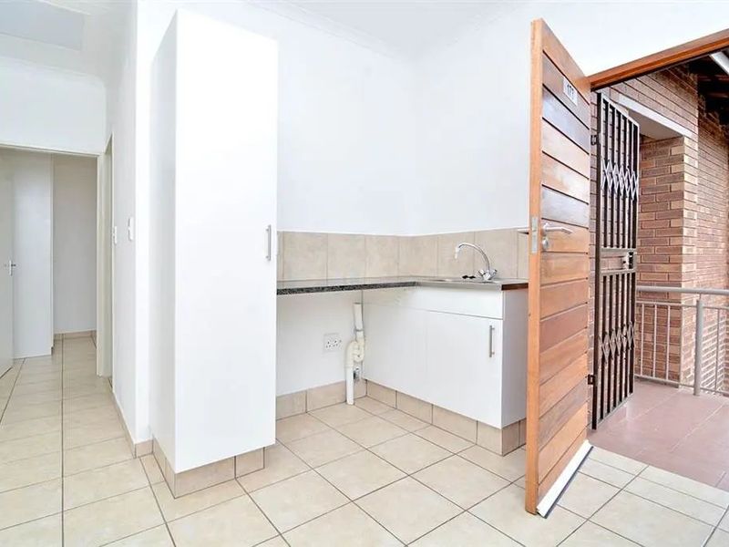 An entrance area featuring tiled flooring, built-in cabinetry with a granite countertop, a sink, and direct access to an external balcony.