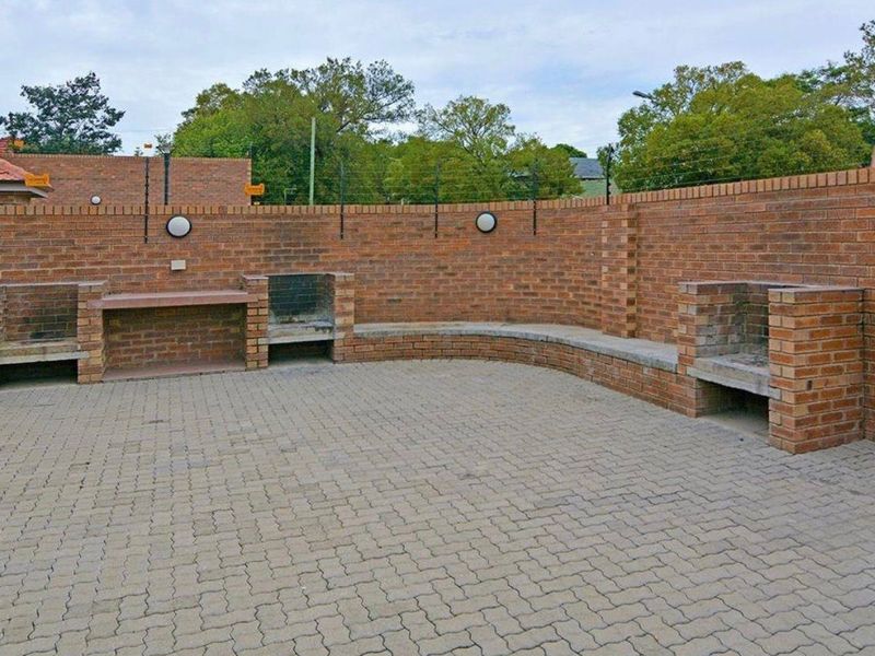 Outdoor entertainment area featuring paved flooring, built-in brick braai stations, and integrated brick seating against a secure perimeter wall.
