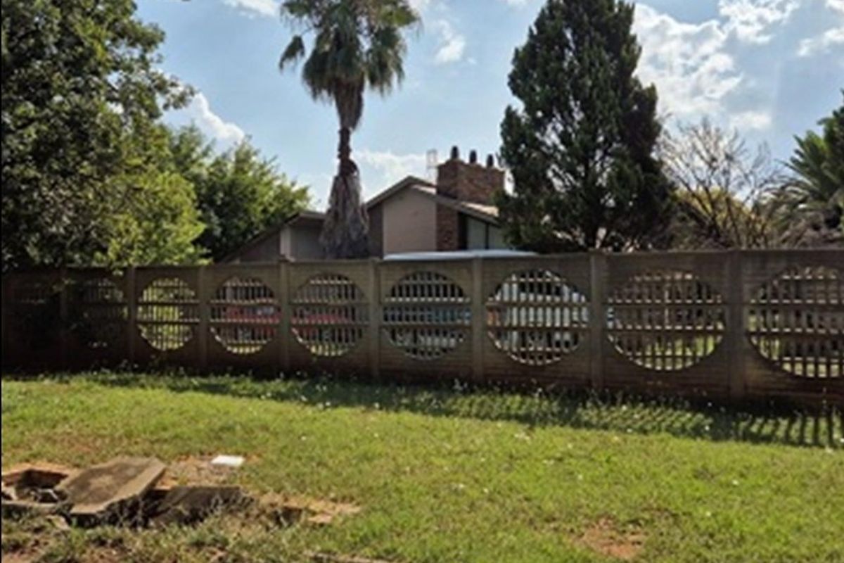 Front view of the property featuring a decorative concrete boundary wall and partial view of the house roofline and chimney.